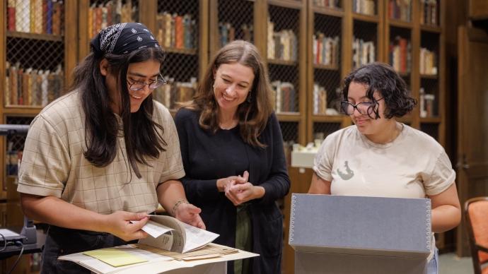 Three people stand over a table of books